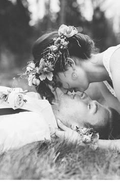 a man and woman laying on the ground kissing each other with flowers in their hair