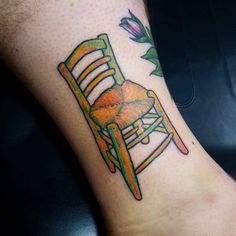 a tattoo on the foot of a person with a chair and flower in it's center