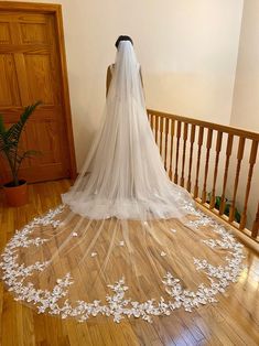 a bride's veil is draped over her wedding dress on the stairs in this photo