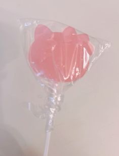 a pink lollipop in a clear plastic wrapper on a white table top