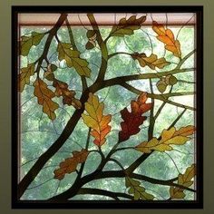 a stained glass window with autumn leaves on the outside and green trees in the background