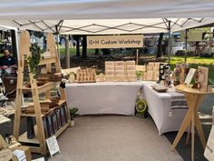 an outdoor market area with tables and shelves full of goods under a tent that says g - h custom workshop