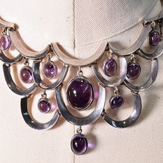 "Gorgeous necklace with a curved design and 10 cabochon set amethyst stones. Handcrafted, hinged, with abox closure on the back accented with an amethyst stone. The drops move very gently with the curved frame of the necklace. It is a beautiful piece. dated 1953-1979; Taxco, Mexico Antonio Pineda was a master silversmith who apprenticed with William Spratling. The maestro's work evolved from an early post-Mexican Revolutionary style influenced by a variety of themes that surrounded him, includin Mexican Silver Jewelry, Amethyst Stones, Mexican Jewelry, American Jewelry, Amethyst Stone, Gold Jewelry Fashion, Gorgeous Necklaces, Vintage Jewellery, Silver Bracelets