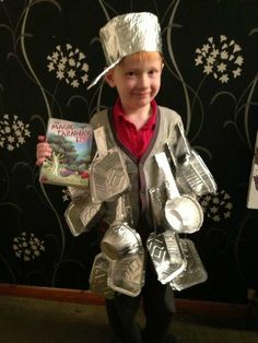 a young boy is dressed in tinfoil and holding a book