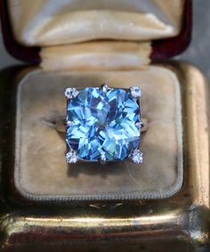 a blue diamond ring sitting on top of a velvet box