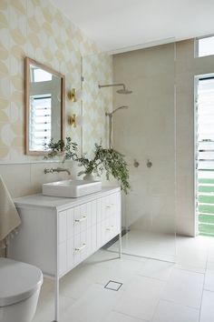 a white bathroom with two sinks and a shower in the back drop off tub area