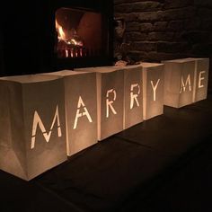 three bags with the words marry me lit up on them in front of a fireplace