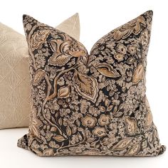 two decorative pillows sitting next to each other