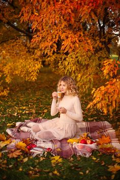 a woman is sitting on the ground with her cup in hand while she eats some food