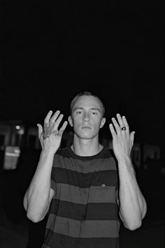 a man standing in front of a black and white photo holding his hands up to the sky