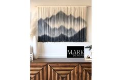 a black and white wall hanging over a wooden dresser