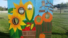 a painted outhouse with sunflowers and pumpkins