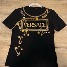 Authentic Versace Tee In Black. Excellent Condition - Like New! Size 44. (Us 8). Versace Tags Attached. Made In Italy. Luxury Gold Short Sleeve Tops, Luxury Black Top With Graphic Print, Luxury Gold Top With Graphic Print, Luxury Gold Tops With Graphic Print, Luxury Fitted Tops With Graphic Print, Versace Tops, Logo Tee, Black Logo, Logo Tees