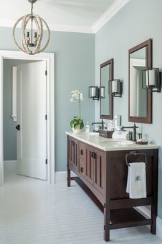 a bathroom with two sinks, mirrors and lights on the wall next to each other