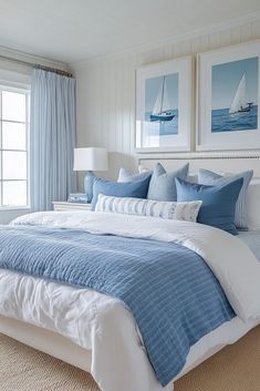 a bedroom with blue and white bedding in front of two pictures on the wall