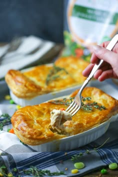 a person is holding a fork and taking a piece of quiche out of the casserole