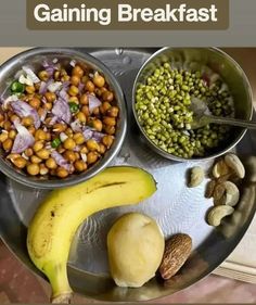 a metal tray topped with bowls filled with food next to a banana and other foods