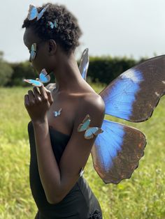 a woman with blue butterflies on her shoulder and chest, standing in a grassy field