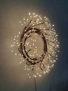 a circular light fixture with white lights in the shape of a wreath on a wall