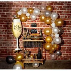 a table with balloons and wine glasses on it in front of a red brick wall