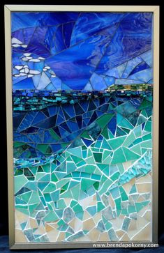 an art piece made out of blue and green mosaic tiles, with the ocean in the background