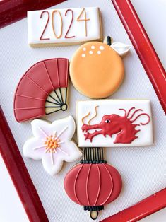 decorated cookies in the shape of chinese zodiacs on a red tray with white background