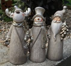 three ceramic figurines in the shape of santa claus and snowmen on a rock