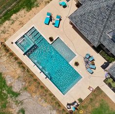 an aerial view of a swimming pool with lounge chairs in the foreground and a house on the other side