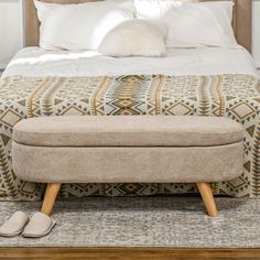 a bed with a footstool and pillows on it