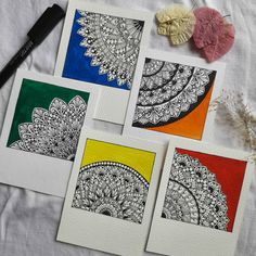 four cards with different designs on them sitting next to a brush and paper doily