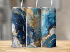 three blue, gold and white vases sitting on top of a wooden table next to each other