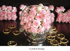 pink roses in a glass vase surrounded by gold wedding rings and love spelled with letters