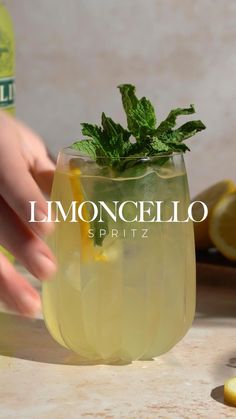 someone is holding a lemon in a glass with ice and mint on the rim that says limooncello spiritz