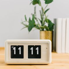 an alarm clock sitting on top of a wooden table next to a potted plant