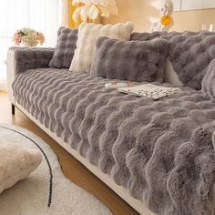 a living room with a couch covered in grey furs and pillows on top of it