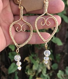 a pair of heart shaped earrings with crystal stones hanging from it's ear wires