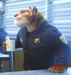 a stuffed tiger is sitting at a table next to a coffee cup and two police officers