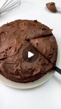 a chocolate cake on a white plate with a spatula in front of the cake