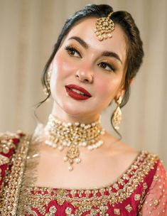 a woman in a red dress with gold jewelry on her neck and headpieces