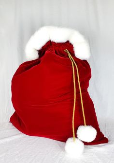 a red bag with white pom - poms on it sitting on a bed