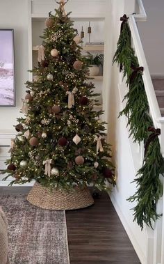 a decorated christmas tree sitting in the corner of a room next to a stair case