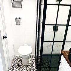 a white toilet sitting in a bathroom next to a walk in shower and tiled floor