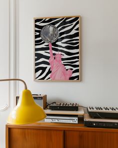 a yellow lamp sitting on top of a wooden table next to a painting and sound equipment