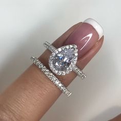 a woman's hand with two engagement rings on her finger and the ring has an oval