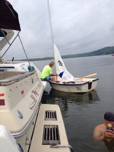 two men in the water with boats and one man taking a drink from a bottle