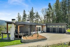 a large house with lots of windows and garages in the front yard, surrounded by trees