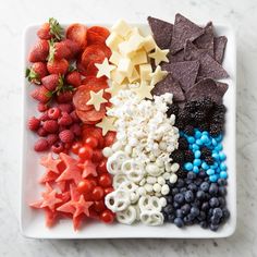 a white plate topped with fruit and veggies next to star shaped crackers