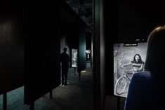 a man standing next to a woman on a bike in a dark room with posters