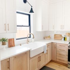 a kitchen with wooden cabinets and white counter tops is pictured in this image, there are plants on the window sill next to the sink