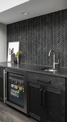 a kitchen with black cabinets and stainless steel appliances in the center, along with an art work on the wall